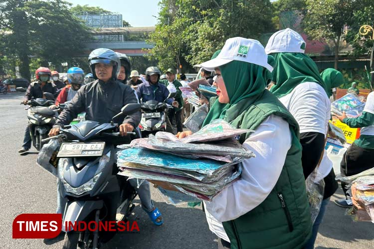 Politisi PKB Surabaya Laila Mufidah bersama relawan saat membagikan kaos dan kerudung kepada pengendara motor yang melintas di depan KBS, Kamis (19/10/2023).(Foto : Lely Yuana/TIMES Indonesia)