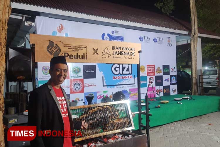 Penyelenggara acara Muhammad Rofiqin saat menunjukkan ikan besar yang tengah di bakar (Foto: Rojihan/TIMES Indonesia)