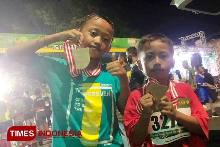 Abyan (kanan) dan Bregas (kiri) dengan bangganya menunjukkan medali Probolinggo Night Run 2023. (Foto: Sri Hartini/TIMES Indonesia)