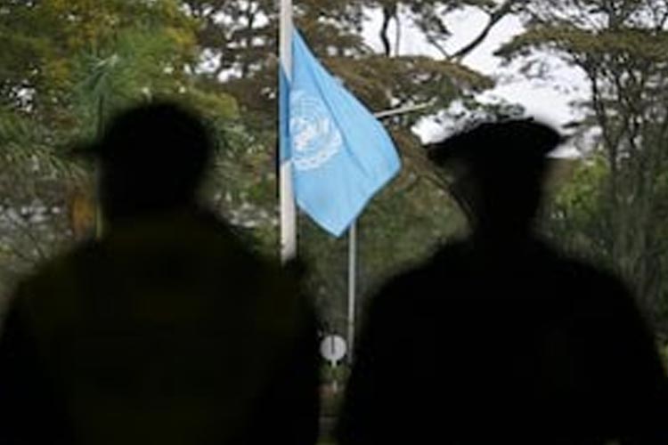 Petugas keamanan menyaksikan bendera PBB berkibar setengah tiang untuk berduka atas nyawa pekerja PBB yang hilang selama perang antara Israel dan Hamas, di Kantor PBB Nairobi (UNON) di Nairobi pada 13 November 2023. (FOTO: AFP)