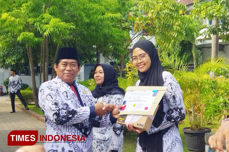 Kepala SMAN 1 Pacitan Adi Supratikto menyerahkan piagam penghargaan kepada guru yang berdedikasi tinggi pada momen peringatan Hari Guru 2023. (FOTO: Yusuf Arifai/TIMES Indonesia) 