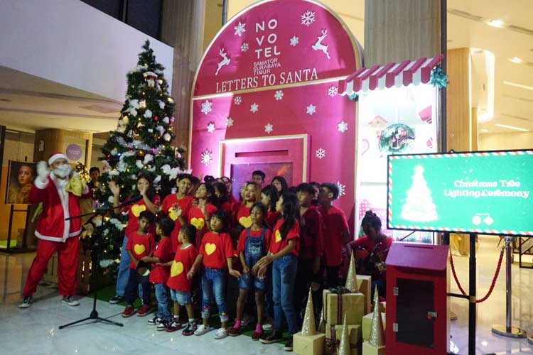 Santa Claus membagi-bagikan kertas kosong beserta amplop kepada anak-anak Panti Asuhan Kasih Agape di Lobby Novotel Samator Surabaya. (Foto: Dok.Novotel Samator)