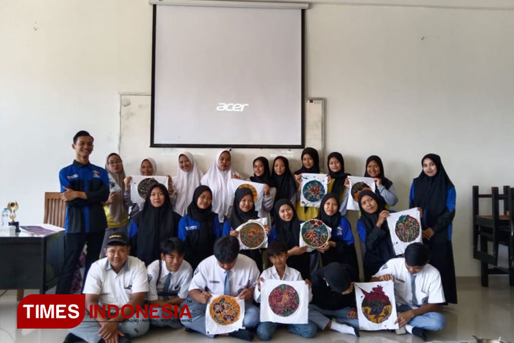 BSO Sanggar Sedaya bersama siswa di MA Al-Hidayah Karangploso menunjukkan hasil batik tulis karya siswa.