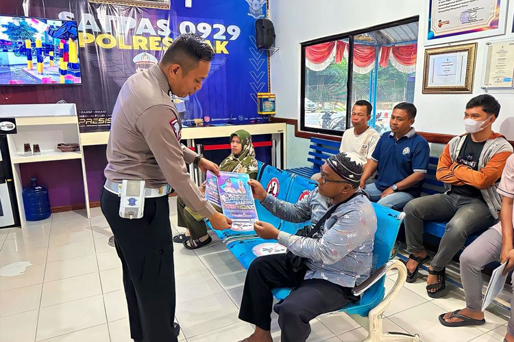 Bripka Hendri, personel Satlantas Polres Siak saat membagi brosur anti Hoax kepada masyarakat. (Foto : Dok Polres Siak for Times Indonesia)