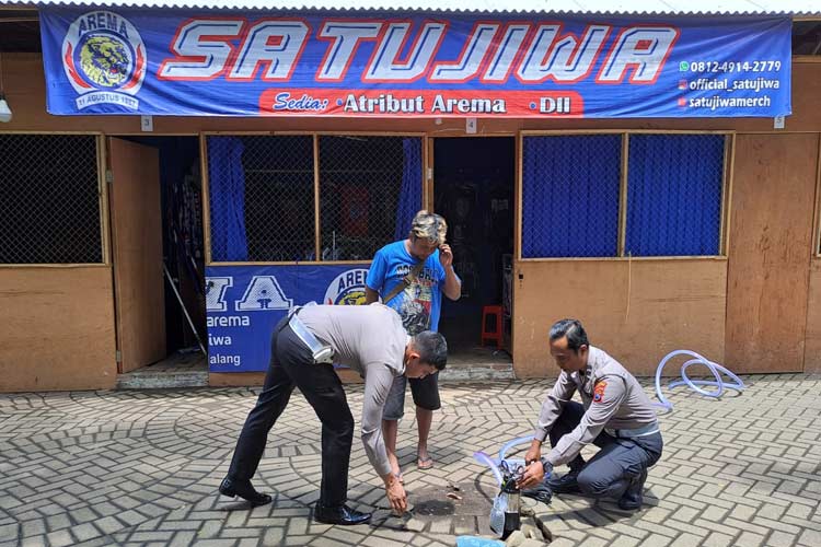 Petugas kepolisian Resor Malang, dibantu salah satu pedagang relokasi kios Stadion Kanjuruhan, saat mencoba mesin pompa sedot portabel untuk mengatasi genangan air di areal berdagang, Selasa (30/1/2024). (Foto Humas Polres) 