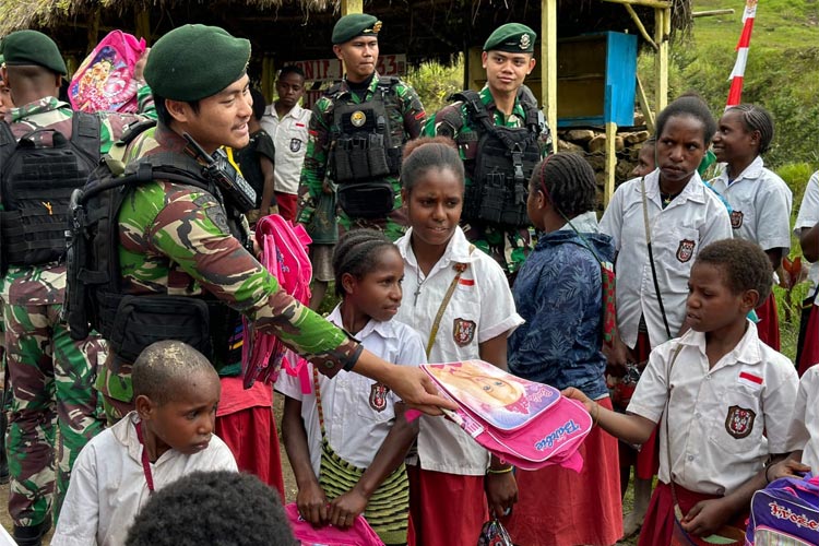 Para prajurit Kostrad yang tergabung dalam Satgas Yonif 433/JS saat membagikan sarana sekolah berupa tas dan alat-alat tulis kepada anak-anak di sekitar Pos Mbua Papua.(FOTO: Satgas Yonif 433/JS untuk TIMES Indonesia)