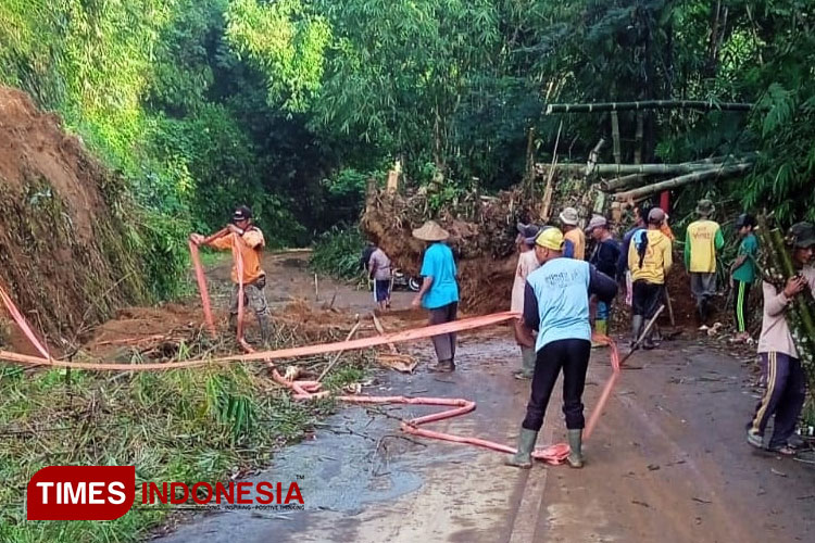 Warga dan petugas berbaur membersihkan tanah yang menutupi jalan yang menghubungkan dua dusun setempat. (FOTO: Hermanto/ Times Indonesia)