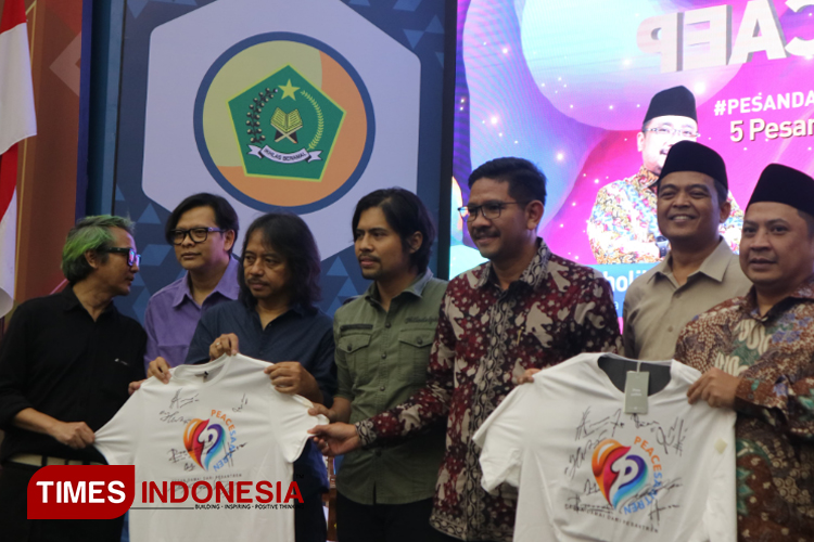 Dirjen Pendidikan Islam Kemenag RI M. Ali Ramadhani (kiri) dan Personel band Gigi menunjukkan Kaos PeaceSantren yang sudah ditandatangani sebagai pertanda dimulainya rangkaian PeaceSantren. (FOTO: Fahmi/TIMES Indonesia) 