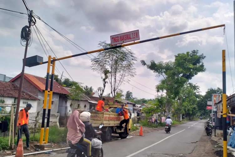 Petugas sedang memasang portal jalan di simpang jalan. (Foto: Kominfo for TIMES Indonesia)