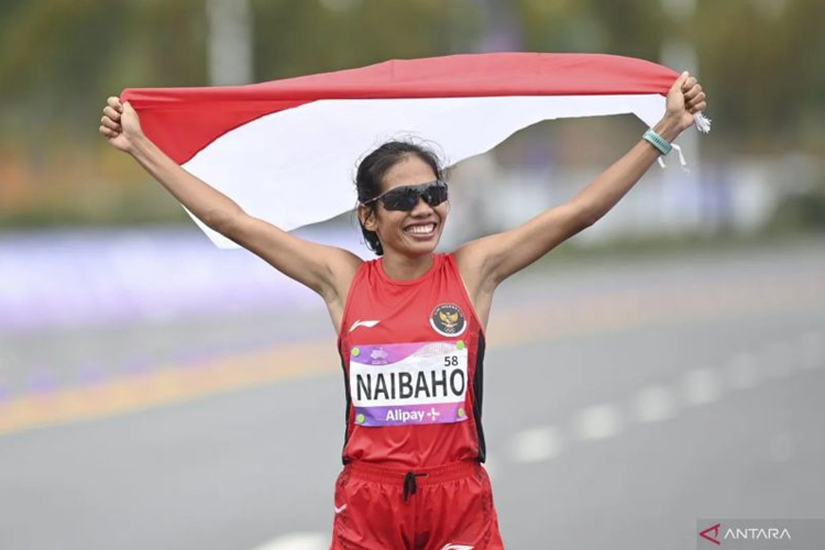 Pelari Indonesia Odekta Elvina Naibaho mengibarkan bendera Merah Putih usai melewati garis finis pada final marathon putri Asian Games 2022 di Qiantang River Green Belt, Hangzhou, China, Kamis (5/10/2023). (ANTARA FOTO/Hafidz Mubarak A)