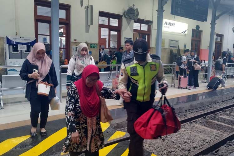 Petugas membantu penumpang arus balik menyebrangi peron di Stasiun Jember. (Humas Daop 9 for TIMES Indonesia)