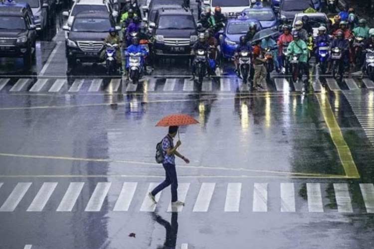 foto arsip:  Seorang pekerja menggunakan payung untuk menghindari hujan saat menyeberang jalan di kawasan Jalan MH Thamrin, Jakarta. (foto: ANTARA/Aprillio Akbar)