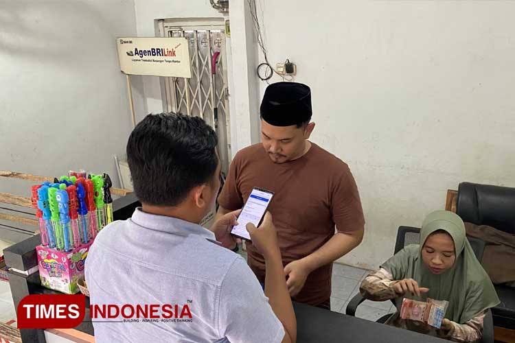 Hikam Yudillah bersama karyawannya saat melayani nasabah di kios Agen BRIlink di Pasar Senin Besuk. (Foto: Abdul Jalil/TIMES Indonesia)