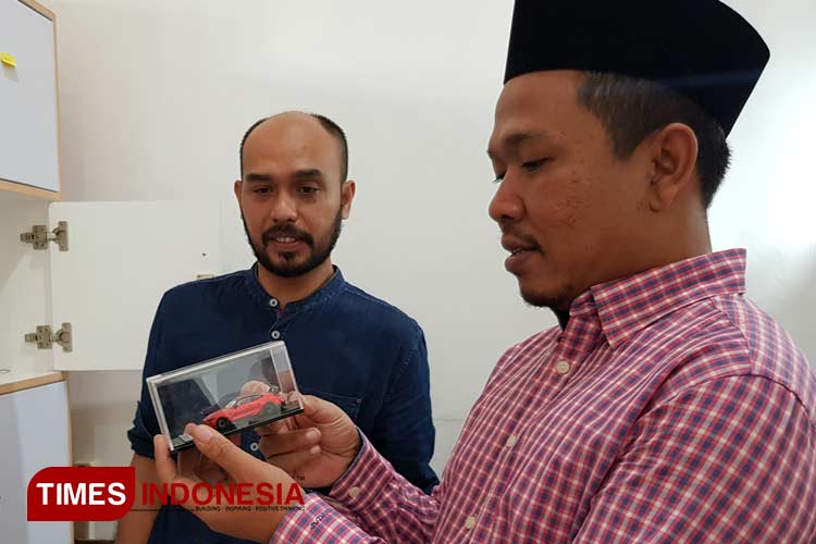 Founder Estungkara Ahmad Hafidh Azkia Alam (baju biru) saat menunjukkan produk miniatur mobil buatanya ke pengunjung. (Foto: Achmad Fikyansyah/TIMES Indonesia) 