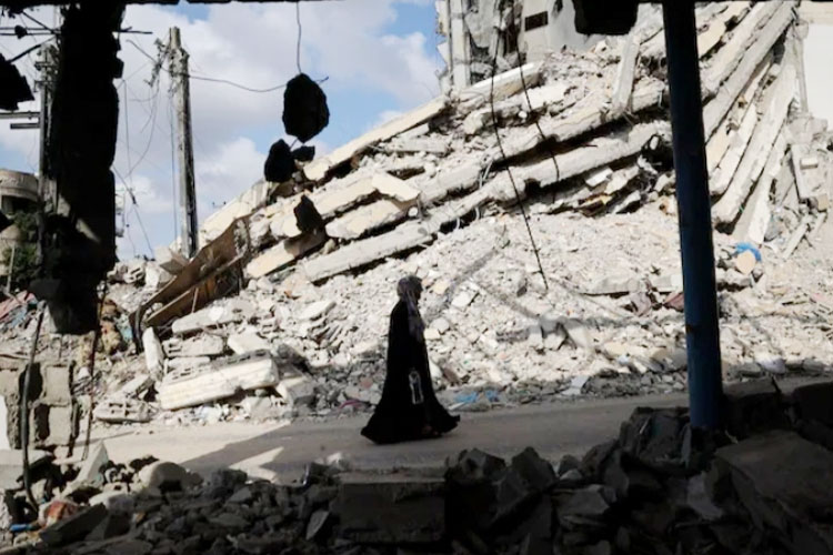 Seorang wanita Palestina berjalan melewati puing-puing bangunan yang hancur di Rafah, Gaza selatan, pada hari Selasa. (FOTO: The Washington Post/AFP/Getty Images)