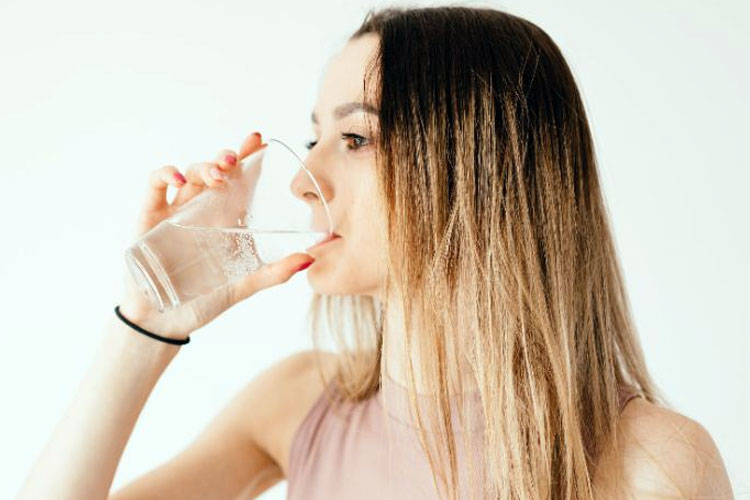 Ilustrasi - Seorang wanita sedang minum segelas air. (Foto: Pexels/Karolina Grabowska)
