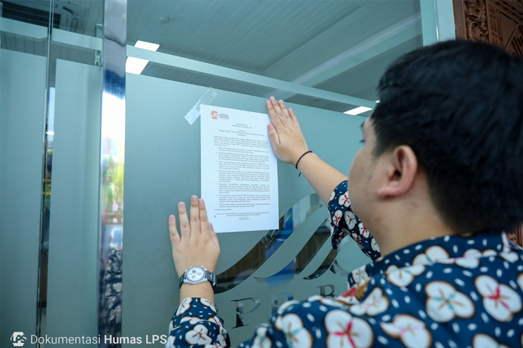 Petugas Lembaga Penjamin Simpanan menempelkan pemberitahuan di pintu masuk BPR Jepara Artha, Jepara,Jawa Tengah. (Foto: LPS for TIMES Indonesia)