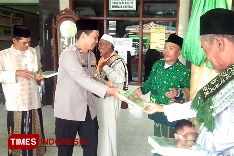 Kapolsek Cerme Iptu Andik Asworo saat membagikan kitab suci Alquran. (Foto: Akmal/TIMES Indonesia).