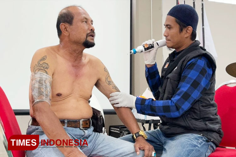 Isrok, petugas penghapusan tato bersama warga yang mengikuti program Penghapusan Tatto Gratis di Masjid Sadji, Kota Malang . (FOTO: Vivid Salsabila/TIMES Indonesia).