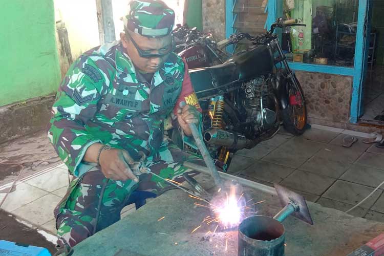 Sertu Agung Babinsa Kecamatan Sukapura saat membantu proses pembuatan kompor oli bekas. (Foto: Sertu Agung for TIMES Indonesia)
