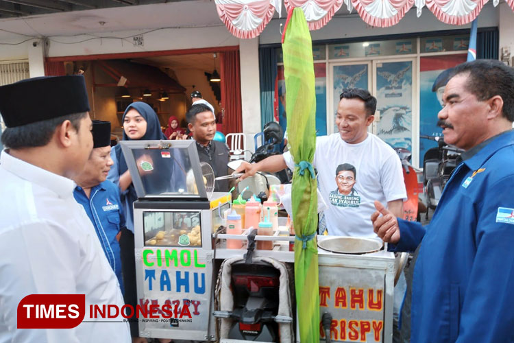 Syahrul Munir bersama Wakil Ketua DPC Partai Demokrat Gresik Suberi saat mencicipi makanan yang dijual PKL (Foto: Akmal/TIMES Indonesia).