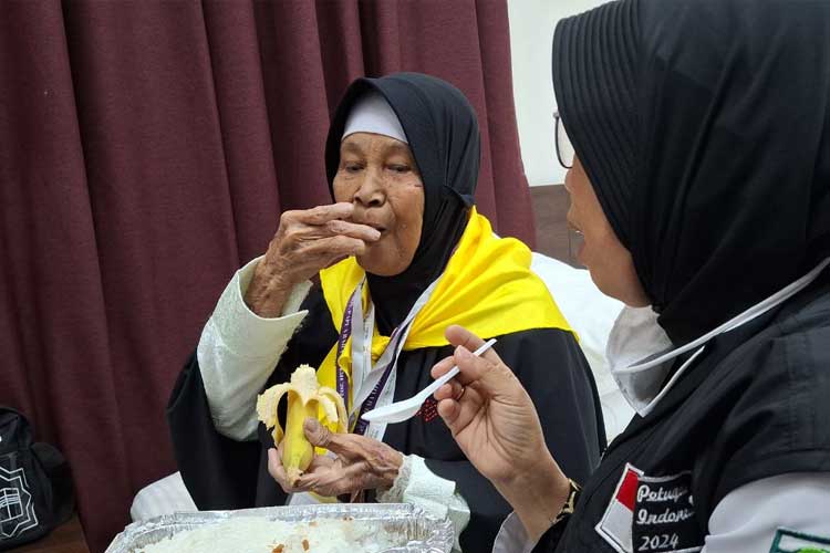 Nenek Zainab, jemaah haji lansia disuapi oleh petugas haji 2024, Fitri. (Foto: MCH 2024 Kemenag RI)