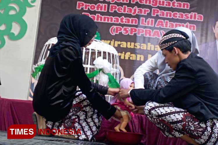 Peragaan prosesi tradisi Tedhak Siten dengan membasuh kaki model boneka anak, oleh pelajar MTsN 6 Malang, dalam kegiatan Gelar Karya P5RA di halaman MTsN setempat, Sabtu (22/6/2024). (Foto: Amin/TIMES Indonesia)