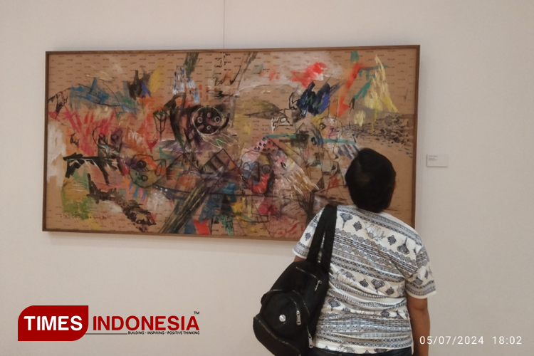 Salah satu pengunjung sedang menikmati karya seni rupa kelompok 7 di pameran Pinarapitu di Galeri Griya Santrian Sanur. (Foto: Susi/TIMES Indonesia)