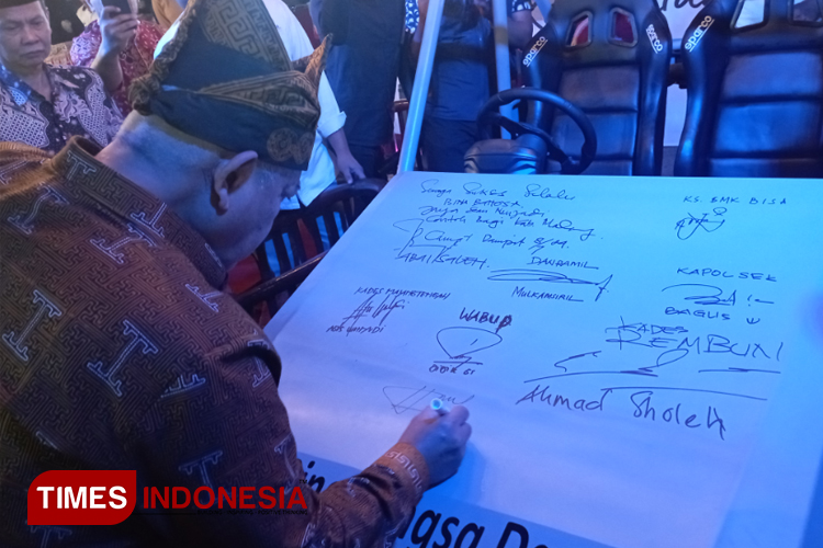 Bupati Malang, HM Sanusi, membubuhkan tanda tangan di kap mobil mini Jeep karya SMK Bina Bangsa Dampit, saat mengunjungi stan Pameran UMKM Explore di lapangan parkir Stadion Kanjuruhan, Kabupaten Malang, kemarin malam. (Foto Amin)