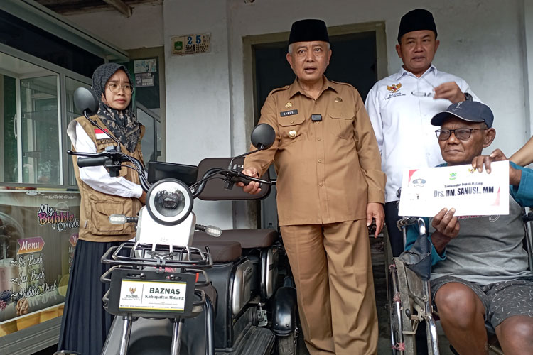 Bupati Malang, HM Sanusi, bersama Ketua Baznas Kabupaten Malang, KH. Khoirul Hafidz Fanani, saat menyerahkan bantuan sepeda listrik roda tiga kepasa Rofii, warga Desa Kemiri, Kepanjen, Selasa (23/7/2024) (Foto: Humas Pemkab Malang)