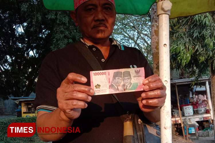 Pedagang ayam, Umar saat menunjukkan uang palsu yang ia terima. (Foto: Rizky Kurniawan Pratama/TIMES Indonesia)