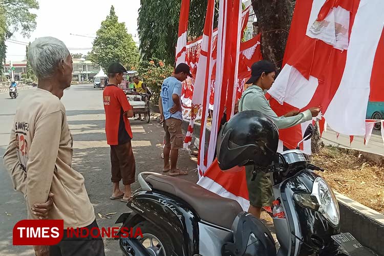 Erna penjual atribut bendera dan umbul-umbul sedang melayani pembeli. (Foto: Ragil/TIMES Indonesia)