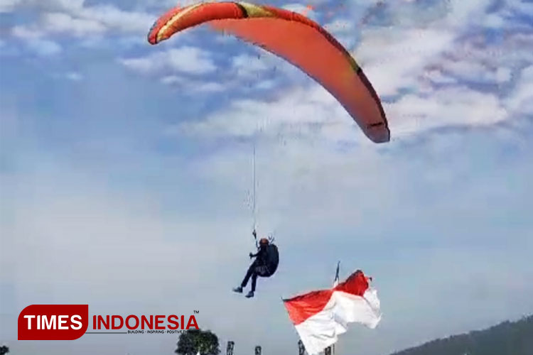 Salah satu atlet paralayang saat mengibarkan bendera di acara TAPA FKPAT 2024 di Kawasan Pasir Datar Galunggung, Sabtu (17/8/2024) (FOTO: Harniwan Obech/TIMES Indonesia)