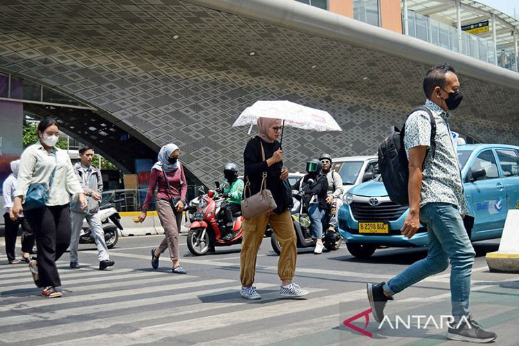 Ilustrasi - Warga menggunakan payung saat menyeberang jalan di area Bundaran HI, Jakarta, pada siang hari yang terik. (ANTARA FOTO/Bagus Ahmad Rizaldi/nz/aa)