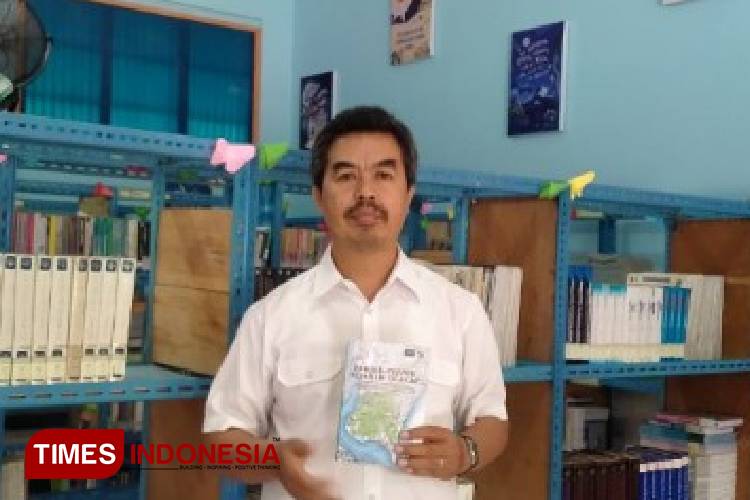 Thomas menunjukkan buku antologi Pernik-pernk Sejarah Cilacap di perpustakaan SMP Pius. (FOTO: Estanto Prima Yuniarto/TIMES Indonesia)