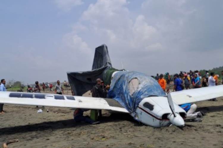 Pesawat latih yang mendarat darurat di Pantai Cemara Sewu, sementara petugas memasang garis polisi. (FOTO: Humas Basarnas Cilacap for TIMES Indonesia)