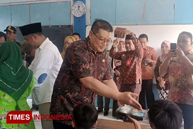Wakil Bupati Malang, Didik Gatot Subroto, bersama anggota Komisi IV DPRD Kabupaten Malang, ikut membagikan makanan bergizi di SDN Penarukan, Kepanjen, Kabupaten Malang, Kamis (5/12/2024). (Foto: Amin/TIMES Indonesia)