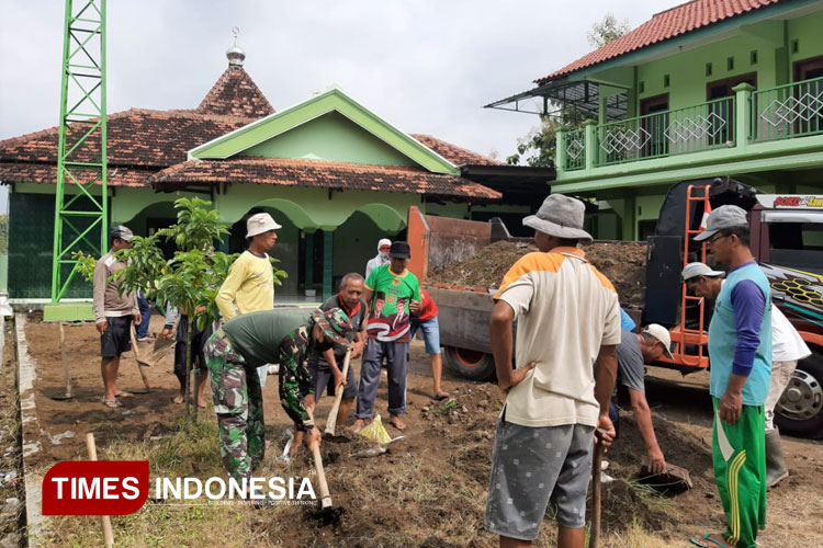 Babinsa Koramil Tipe B 0802/06 Sukorejo, Kodim Ponorogo, Serka Bambang bersama warga menguruk halaman masjid. (FOTO : Pendim Ponorogo for Times Indonesia)