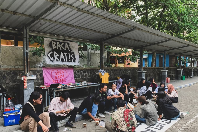 Pengunjung ABS yang sedang membaca dan berdiskusi di selasar Fakultas Sastra UM (Foto: Instagram @areabacaselasaaaaa)