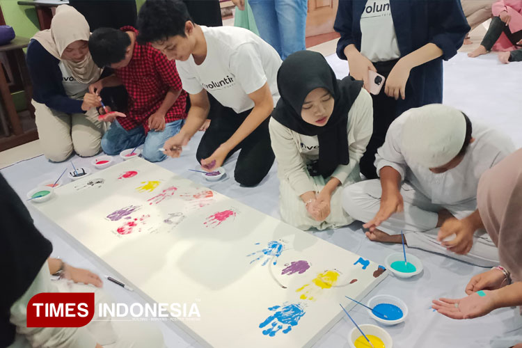 Relawan bersama adik-adik penderita down syndrome sedang menorehkan cap tangan dan harapannya pada kanvas di Child Center House of Fatima Malang, Minggu (16/03/2025). (FOTO: Cindy Audylia Herawati/TIMES Indonesia)