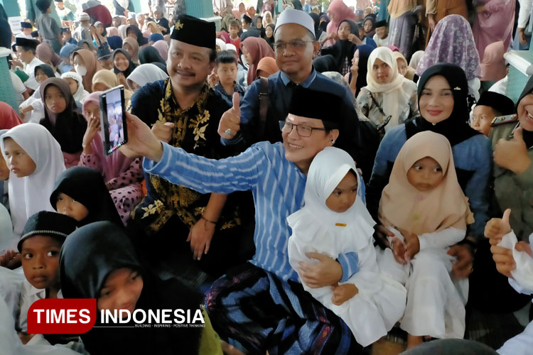 Dengan memangku seorang anak yatim, Komisaris PT ACA, Iwan Kurniawan menyempatkan diri mengambil gambar saat berada di Turen.(FOTO: Widodo Irianto/TIMES Indonesia)