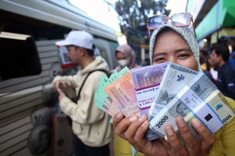 Warga menunjukan uang rupiah baru yang baru saja ditukarkan pada mobil kas keliling Bank Indonesia (BI) (Foto: ANTARA FOTO/Muhammad Iqbal)