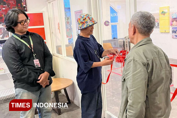 Proses pemotongan pita oleh seniman Djoeari Soebardja pada Pameran Temu Tinemu The Chapter Of Music yang resmi digelar di Astaloka Coffeeshop, Kota Malang pada Jumat (2/5/2025). (Foto: Kamiliya Salsabila Imelda/TIMES Indonesia)