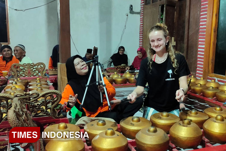 Turis dari Inggris mencoba menabuh gamelan saat mengunjungi Rumah Gamelan Sulistyo Laras. (Foto: Yupi Apridayani/TIMESIndonesia)