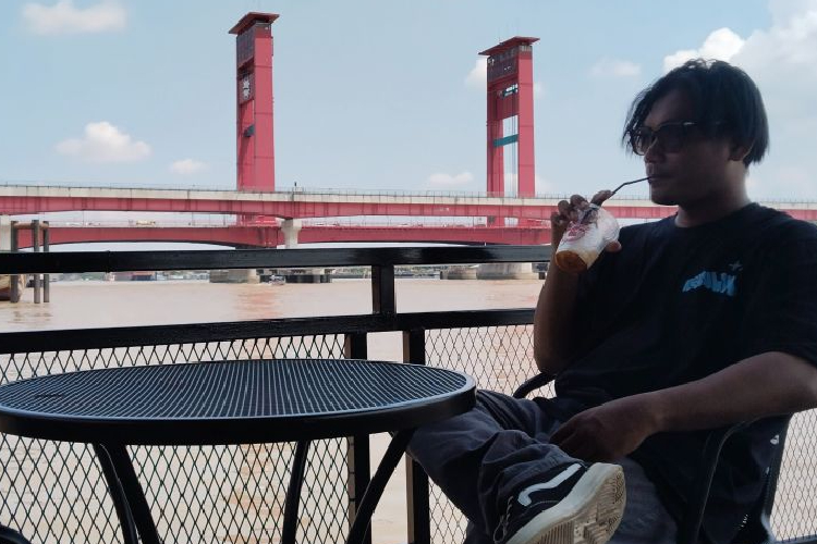 Seorang penunjung kafe di pinggir Sungai Musi, Kota Palembang, sedang menikmati suasana sore, Sabtu (9/5/2025). (FOTO: ANTARA/M Imam Pramana)