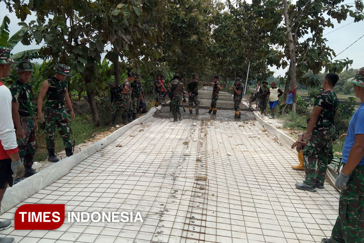 Satgas TMMD ke-124 sedang melakukan pemasangan besi rap dan bagasting untuk rabat beton. (Foto : Pendim Lamongan for Times Indonesia)