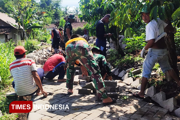 TNI bersama masyarakat gotong royong pemasangan paving di jalan Dusun Plalangan. (FOTO : M.Abdul Basid / TIMES Indonesia).