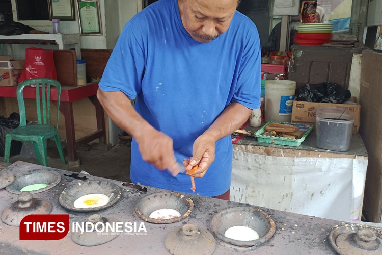 Hariyanto, sang pemilik Surabi Imut sedang membuat pesanan dengan beberapa topping di tungku legendarisnya (Foto: Cindy Audylia Herawati/TIMES Indonesia)