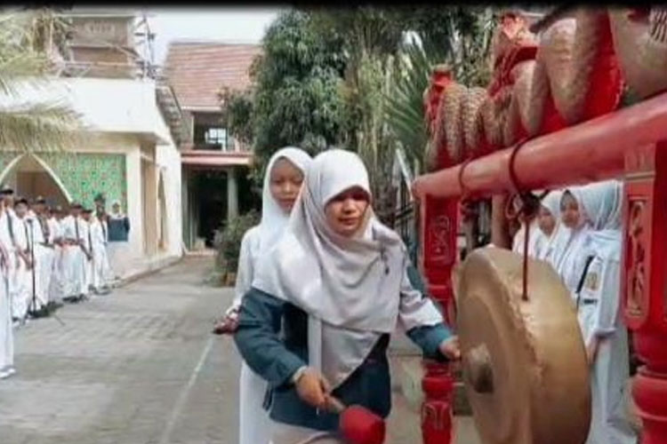 Lilik Farida, S. Pd, Waka kurikulum SMP PGRI 1 Bululawang saat membuka MPLS yang ditandai dengan pemukulan gong, Senin (14/7/2025). (Foto: Slamet Mulyono for TIMES Indonesia)