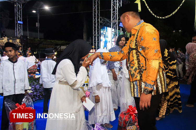 Kapolres Malang AKBP Danang Setiyo P.S. menyerahkan santunan pada anak yatim piatu sebelum pagelaran wayang kulit, puncak Hari Bhayangkara ke-79 di Polres Malang, Sabtu (19/7/2025) malam. (FOTO: Humas Polres Malang for TIMES Indonesia)